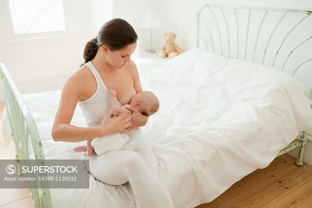 Mother breast feeding baby on bed