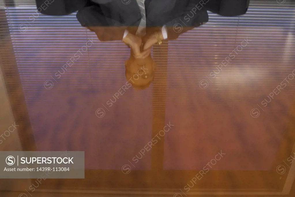 Businessman reflected in glass table