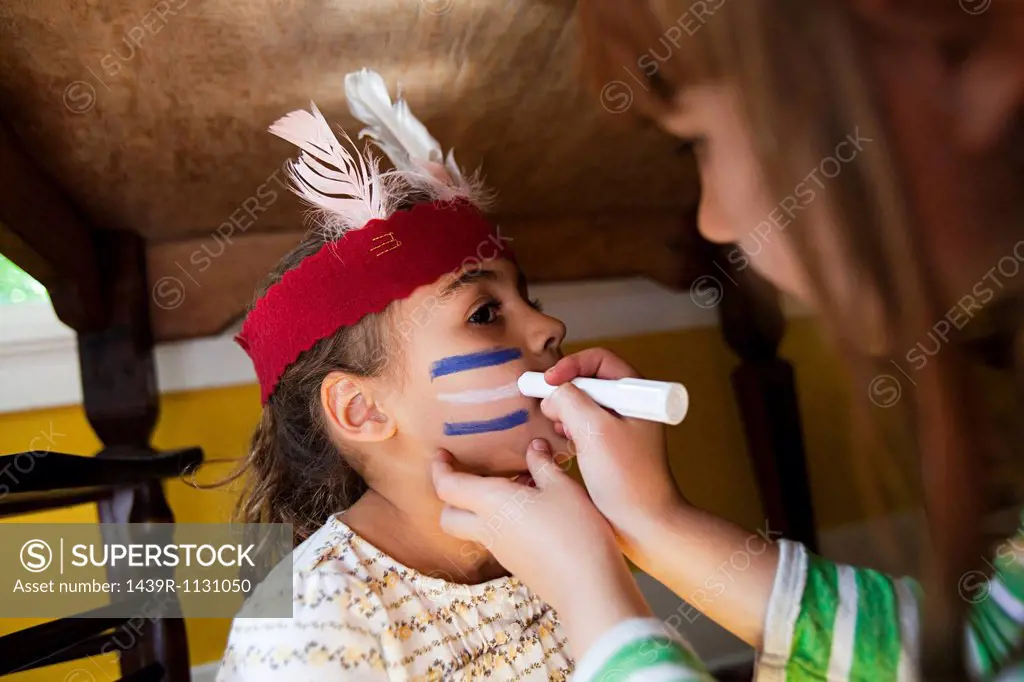Girl putting Native American face paint on another girl