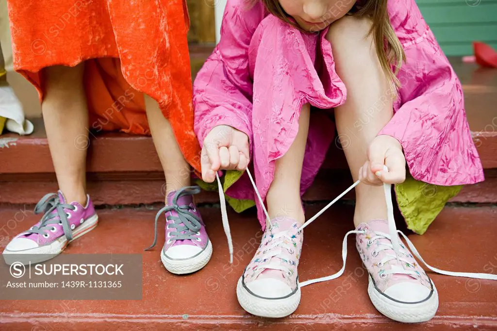 Two girls, one tying up shoelace