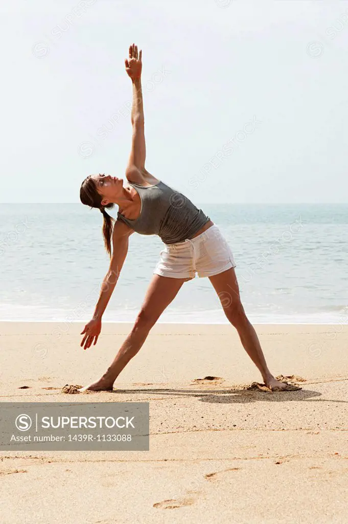 Woman practicing yoga on a beach