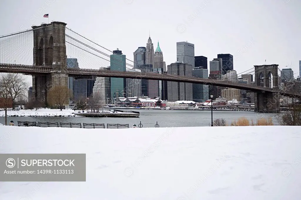 Brooklyn bridge and manhattan buildings in the snow