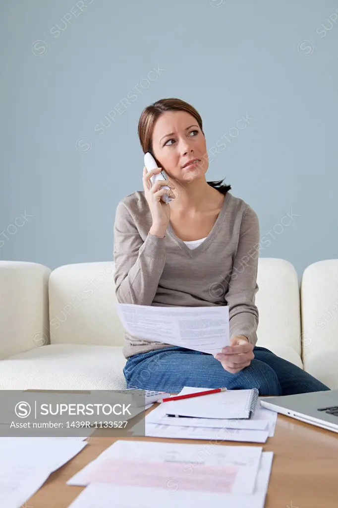 Young woman on the phone with paperwork