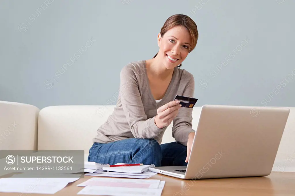 Young woman with credit card using laptop