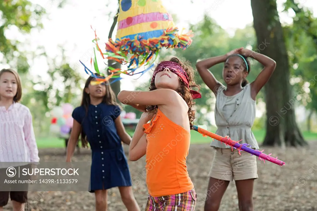Girl at birthday party hitting pinata
