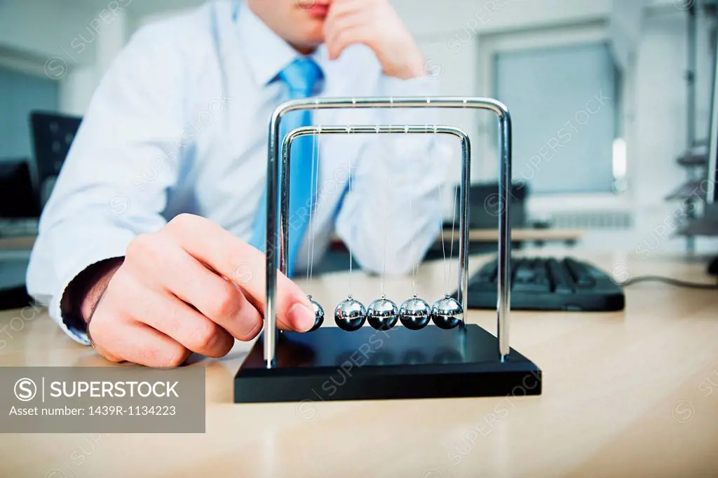 Office worker playing with newtons cradle