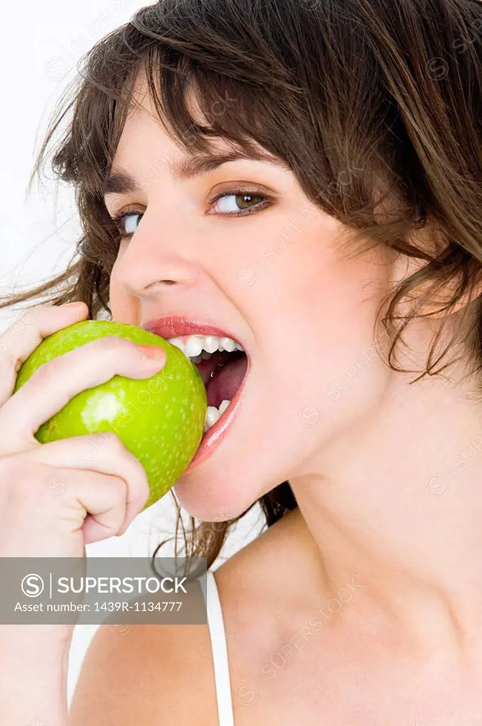 Portrait of young brunette woman eating apple