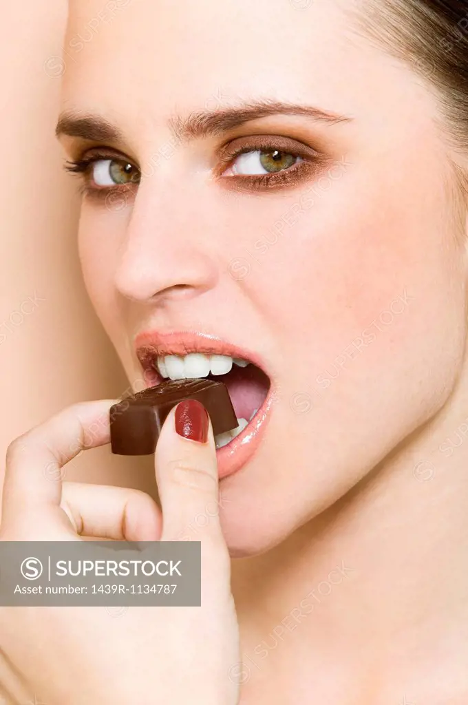 Young woman biting chocolate