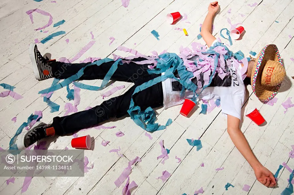 Man lying on floorboard covered with streamers at party