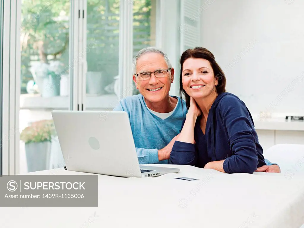 Mature couple using laptop with credit card