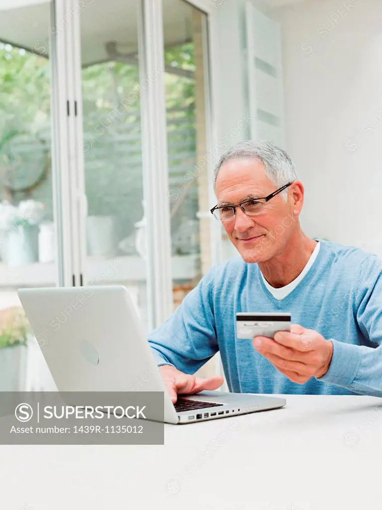 Senior man using laptop with credit card