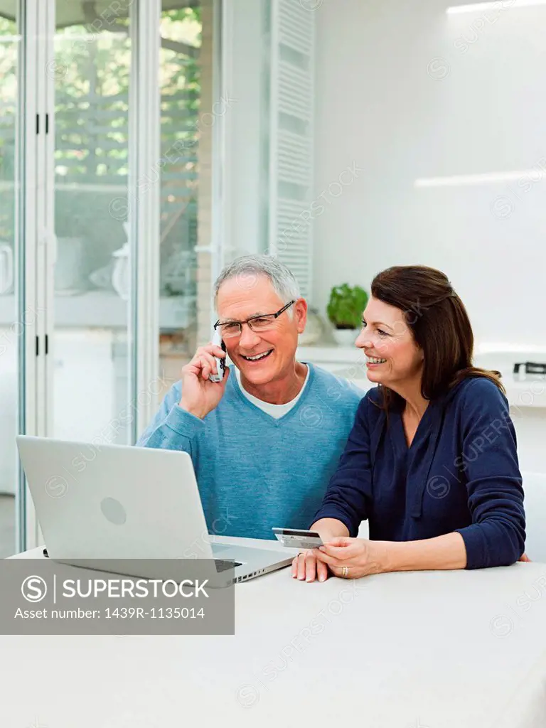 Mature couple using laptop with credit card