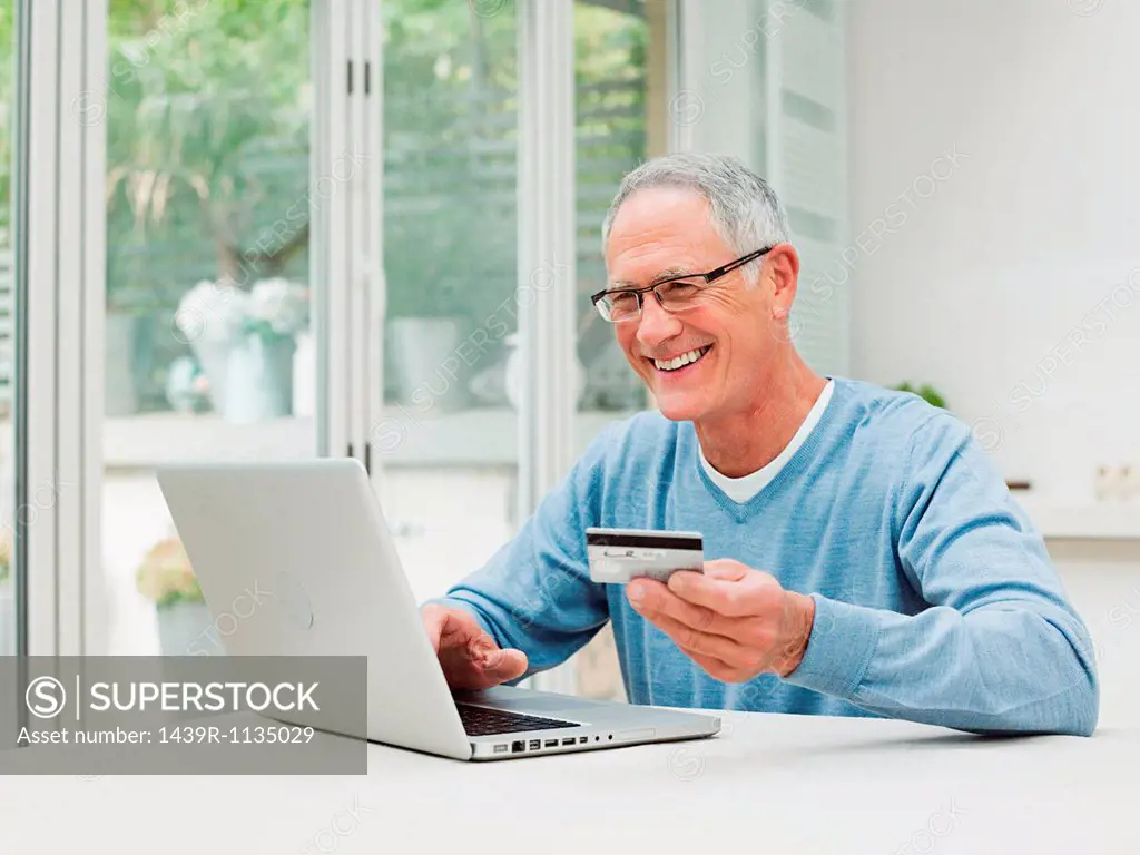 Senior man using laptop with credit card