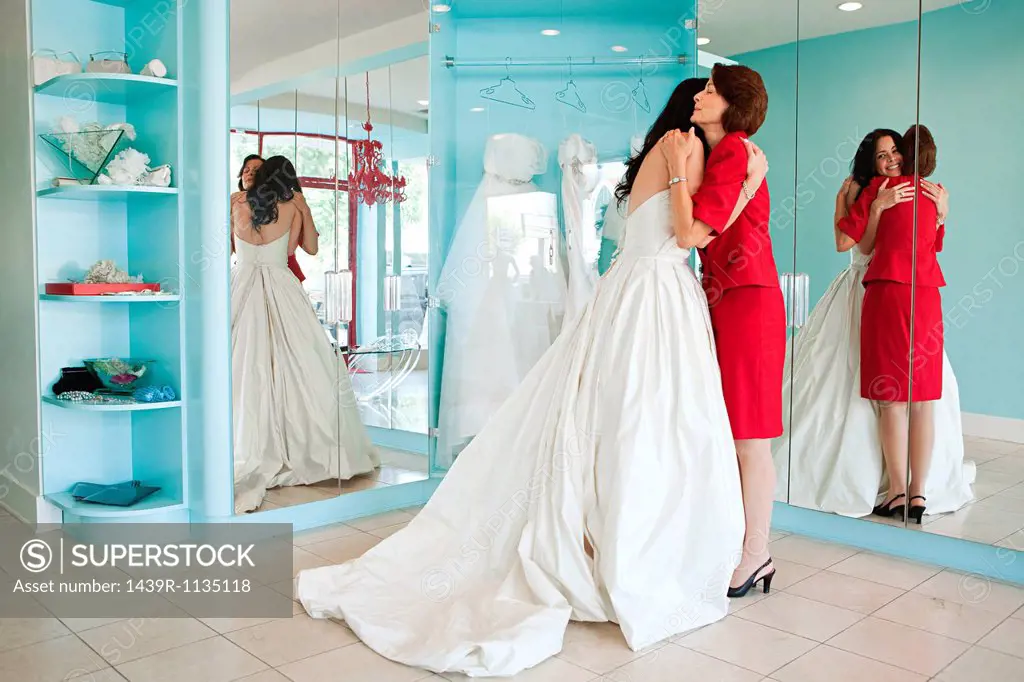 Daughter trying on wedding dress, embracing mother