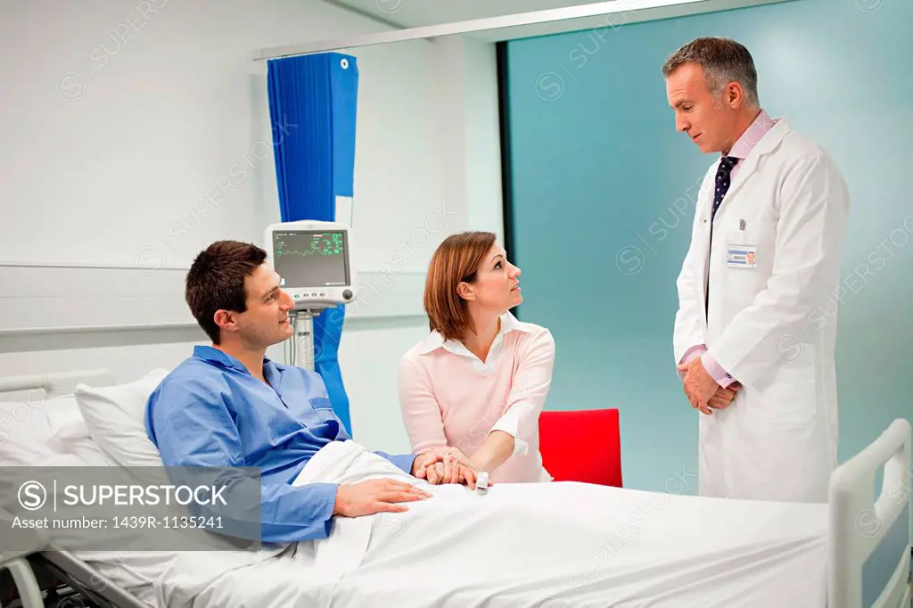 Wife visiting husband in hospital, talking to doctor