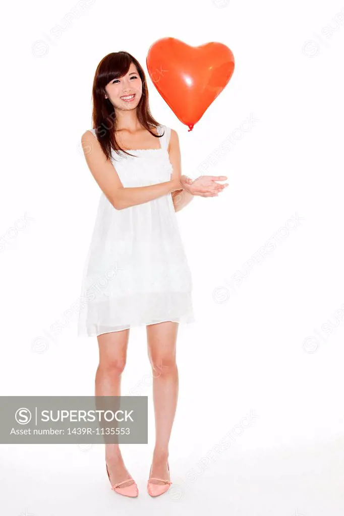 Woman holding red heart shaped balloon, studio shot