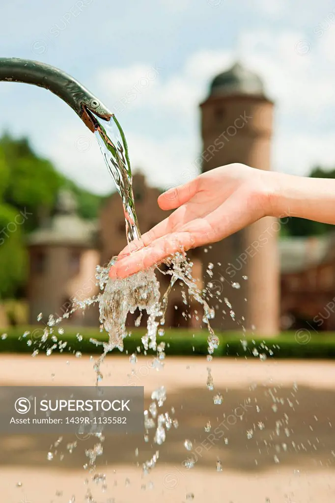 Woman with hand in water fountain, close up