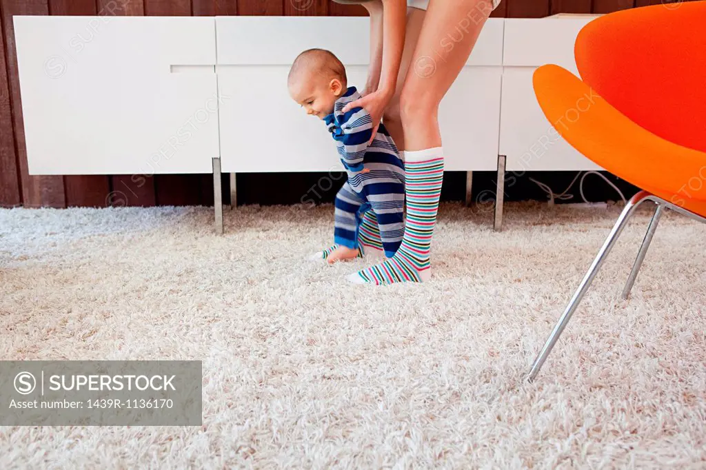 Mother helping baby son take first steps
