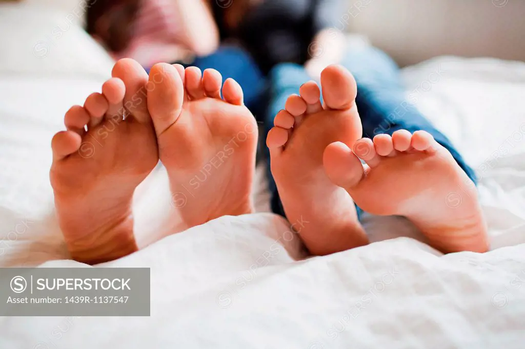 Two teenage girls lying on bed barefoot