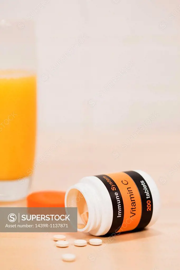 Glass of orange juice and vitamin c tablets