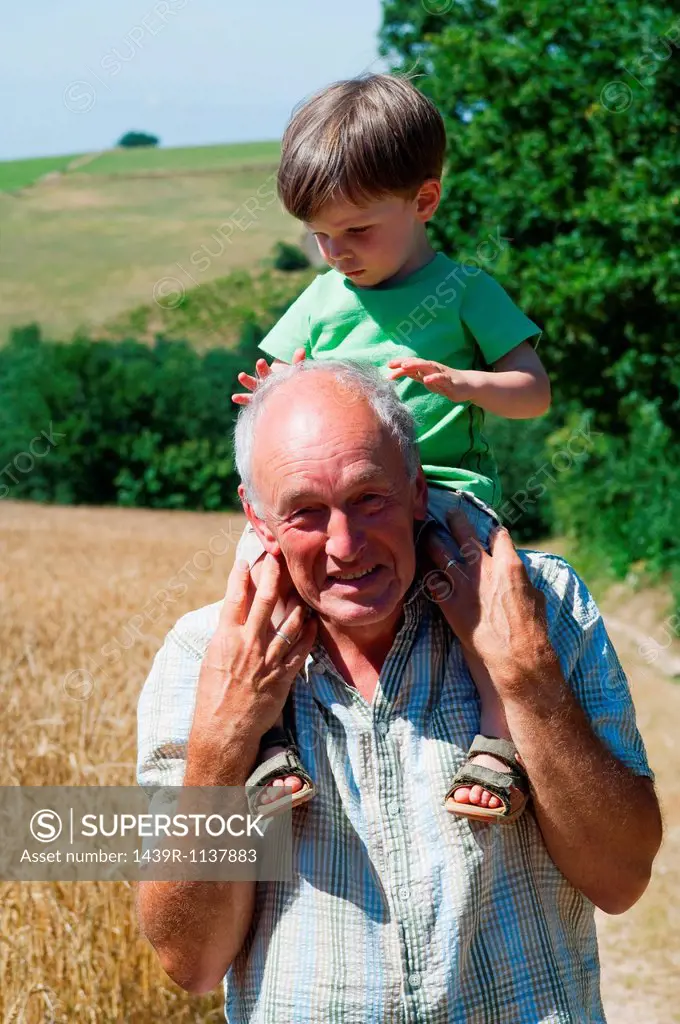 Grandfather carrying grandson on shoulders, portrait