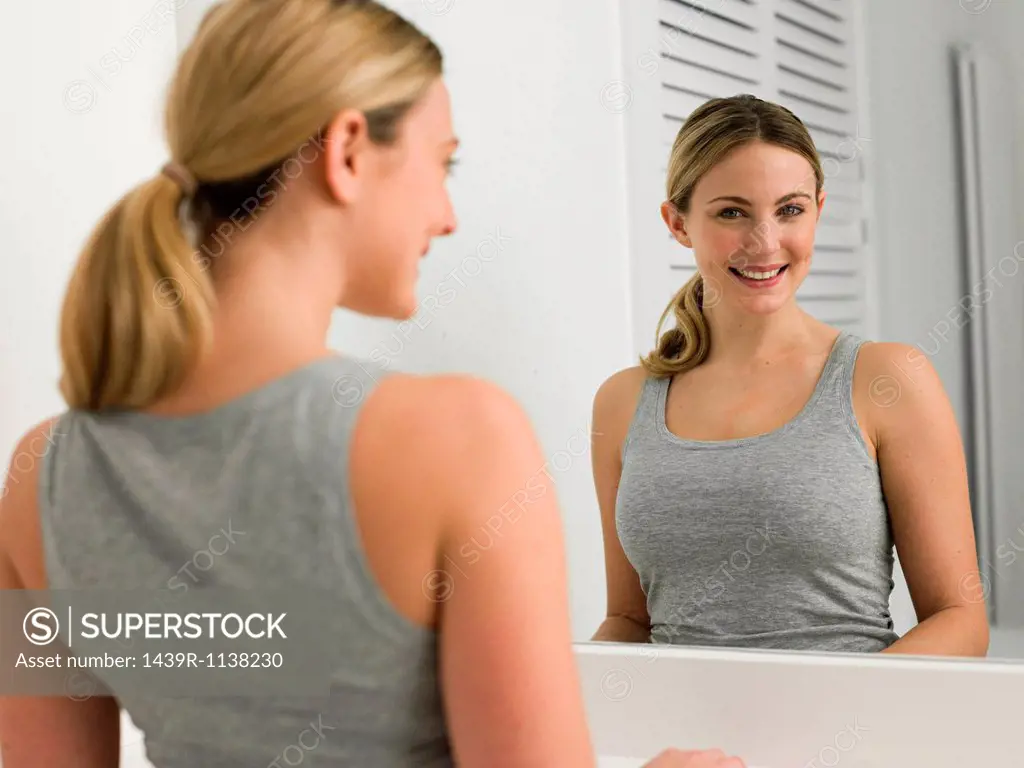 Reflection of young woman in bathroom mirror