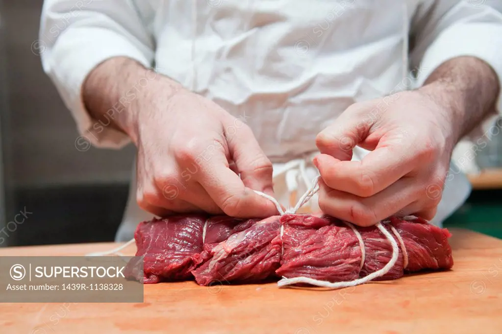 Butcher tying beef tenderloin with string