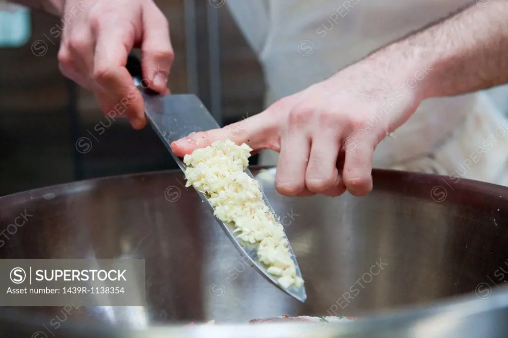 Chef adding diced onions to bowl