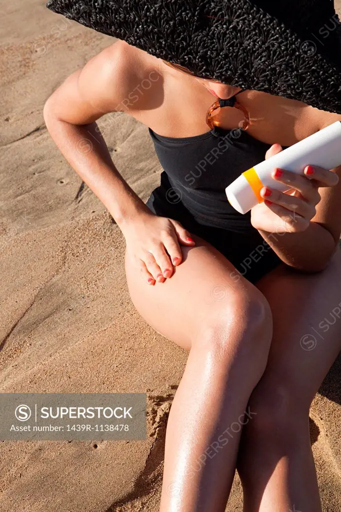 Young woman applying sun cream on beach