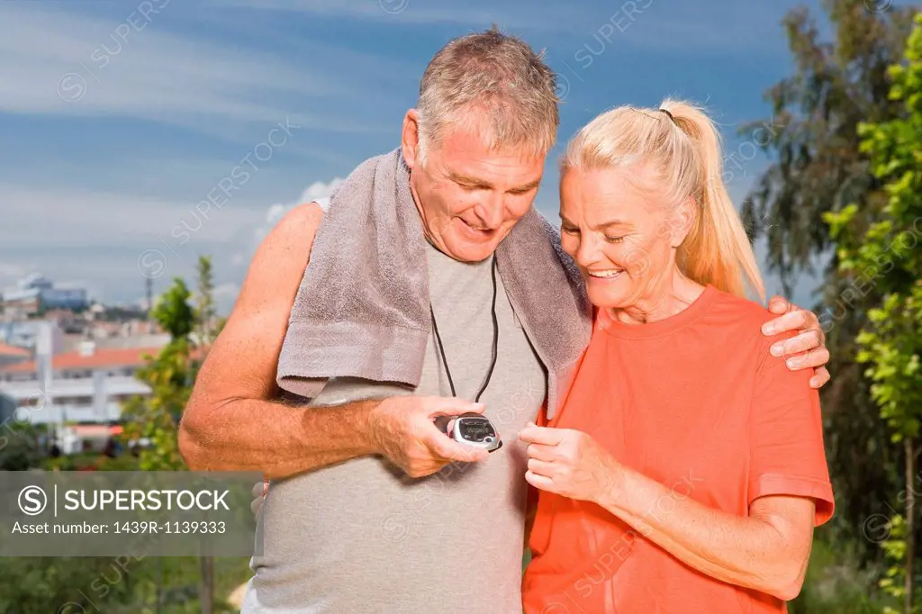 Mature couple looking at stopwatch after workout