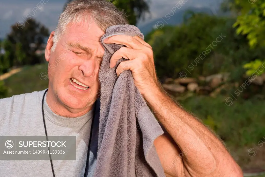 Senior man wiping face with towel after workout