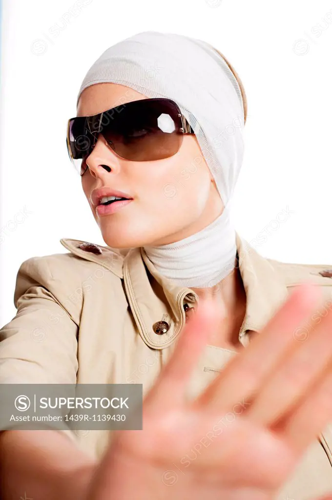 Young woman in sunglasses and bandages after cosmetic surgery