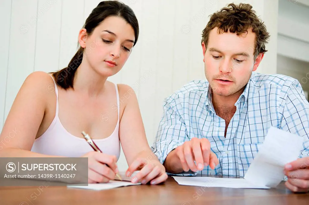 Couple planning home finances, woman writing cheque