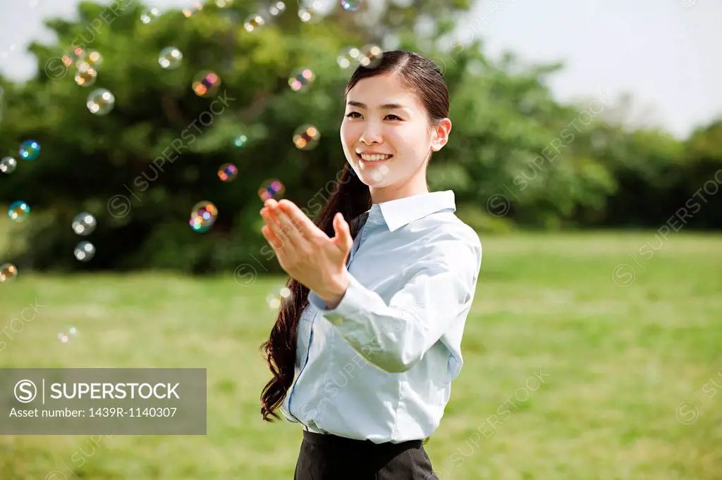 Portrait of young businesswoman touching bubbles