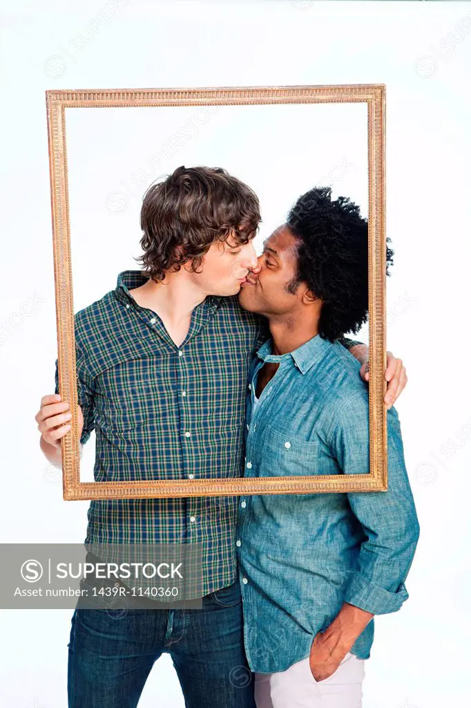 Gay couple kissing with picture frame against white background