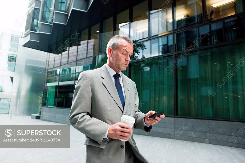 Businessman walking with smartphone and coffee