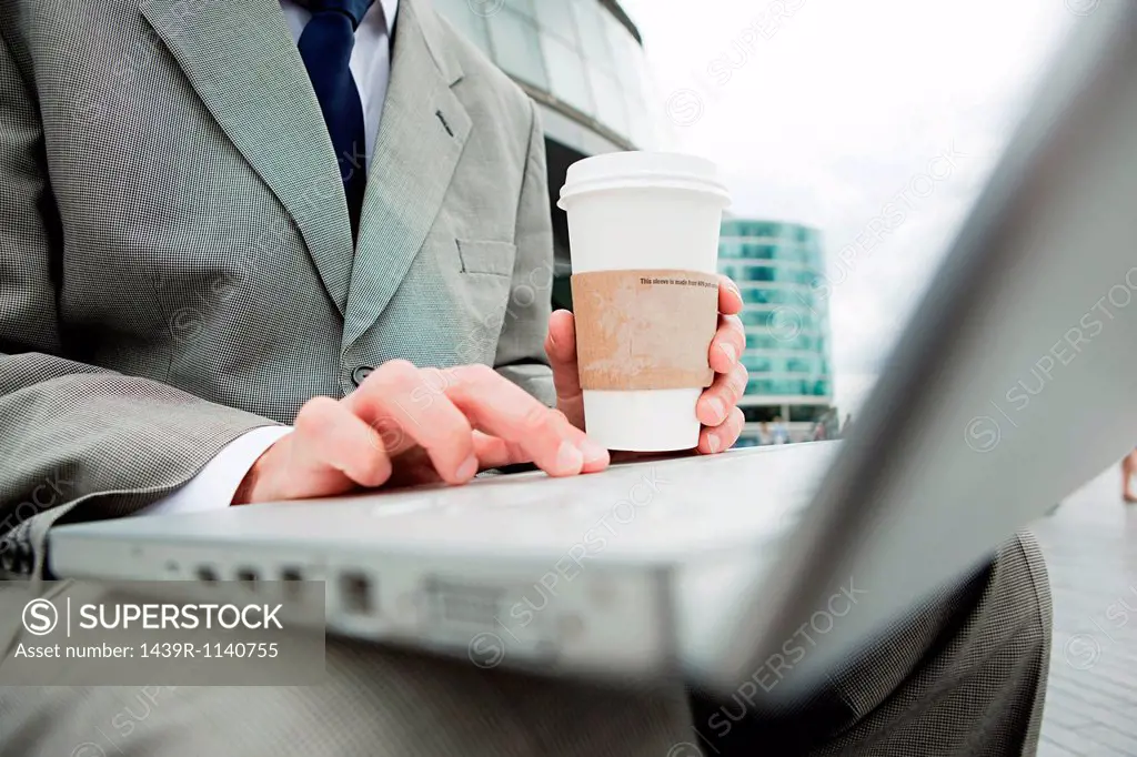Close up of businessman with laptop and coffee outdoors