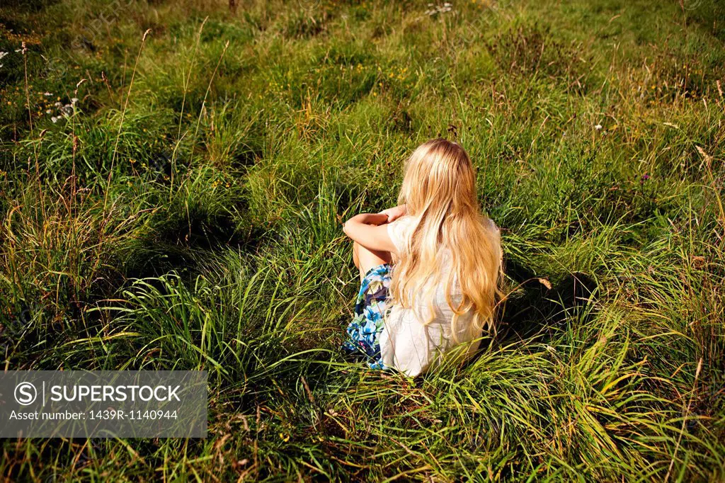 Young woman sitting peacefully in a field