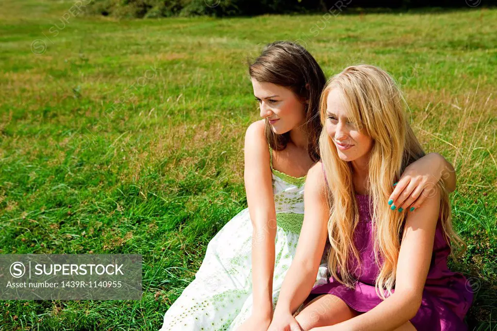 Young lesbian couple sitting side by side in a field