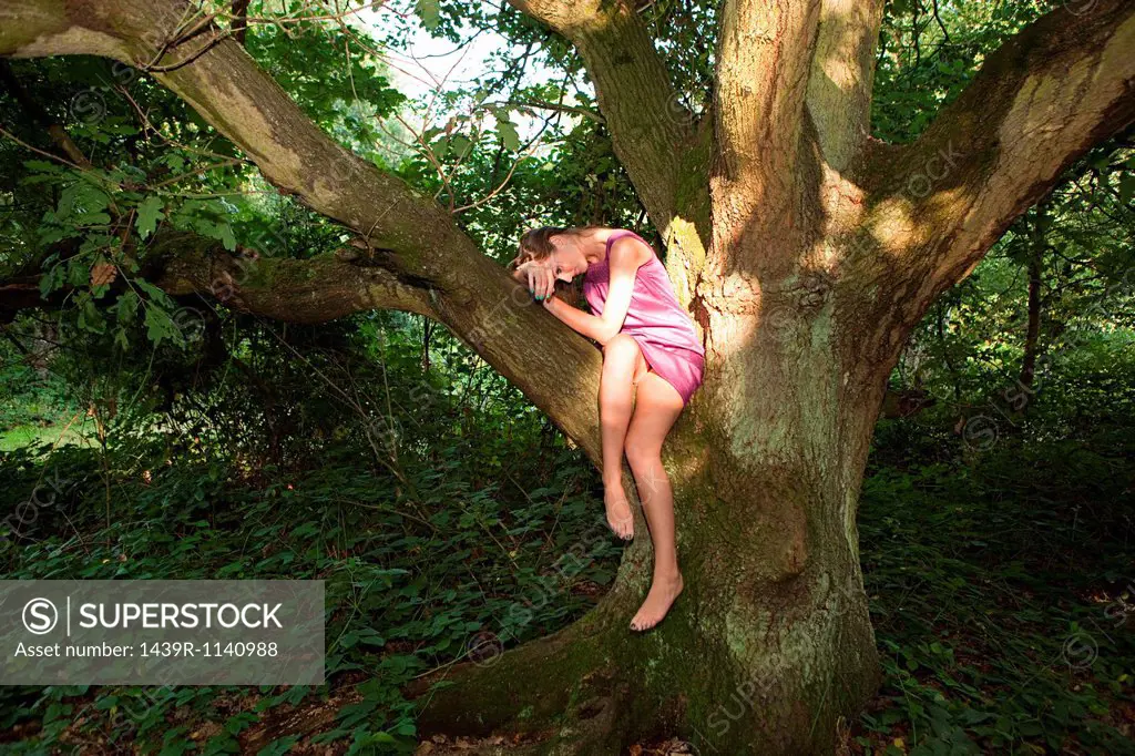 Young woman draped in an old oak tree