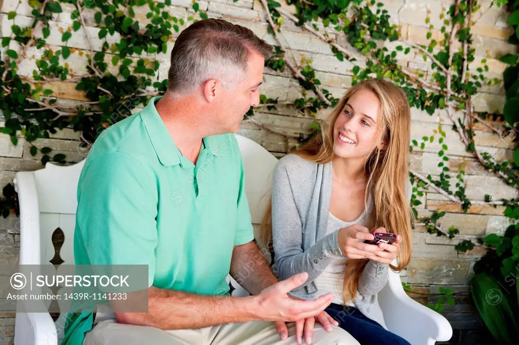 Mature man and daughter sitting together outside