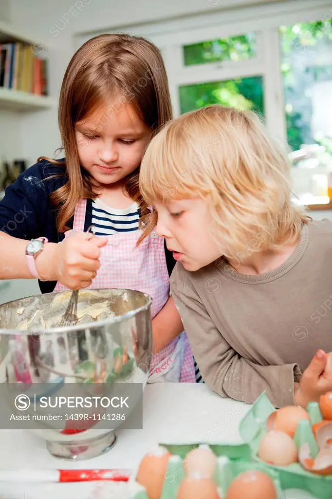 Boy watching sister mix cake ingredients