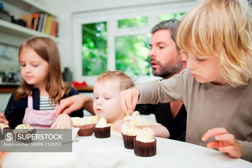Mid adult man and family decorating cupcakes
