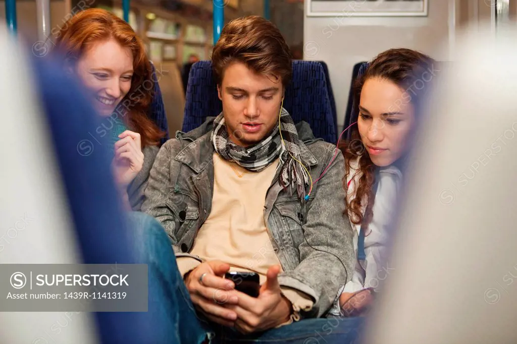Three young friends travelling on train listening to music
