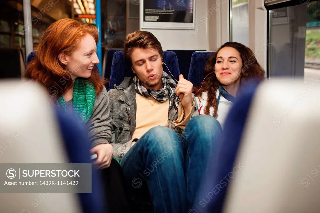 Three young friends travelling on train listening to music