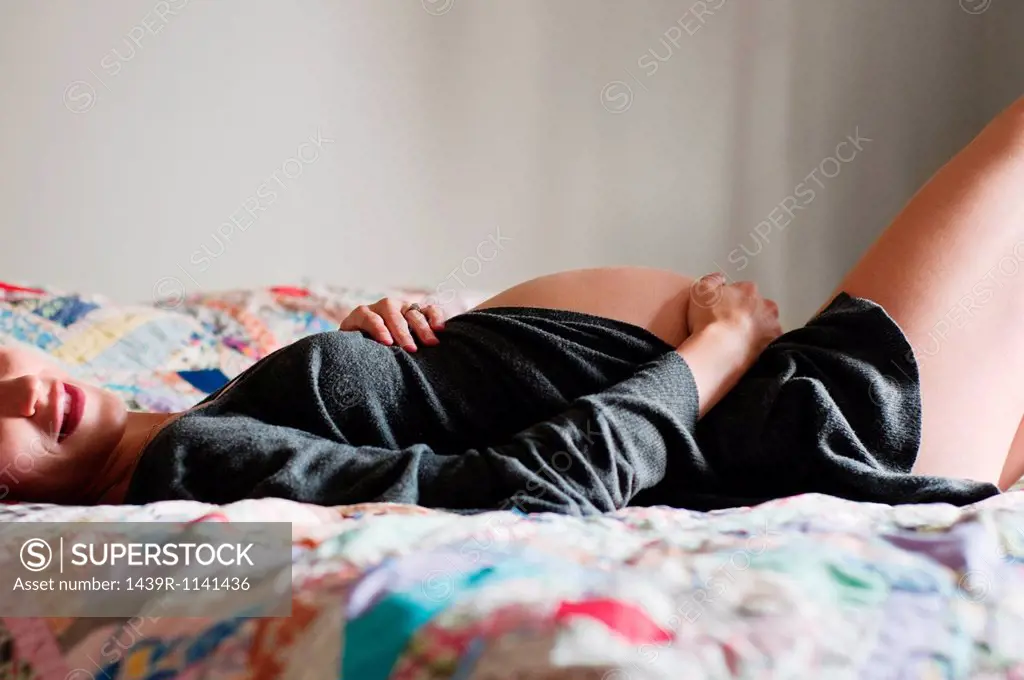Young pregnant woman lying on bed