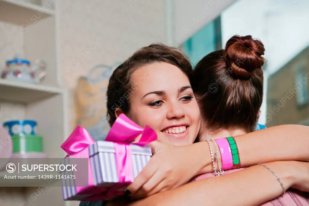 Young women holding birthday gift and embracing