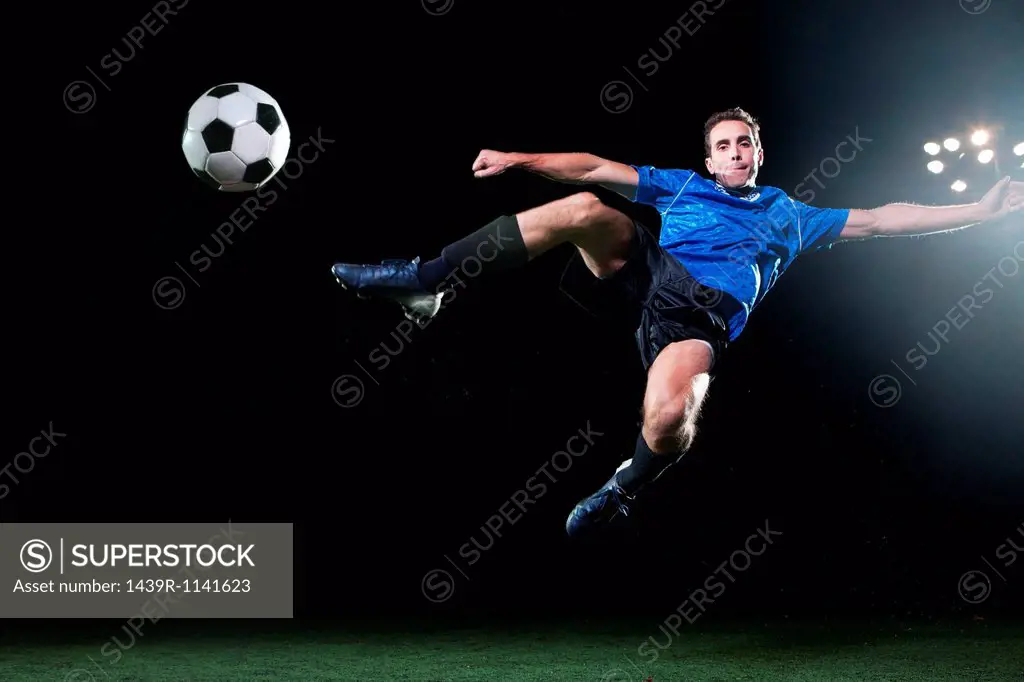 Young soccer player leaping into air to kick ball
