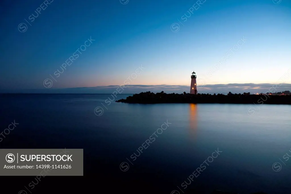 Lighthouse overlooking calm water at dusk