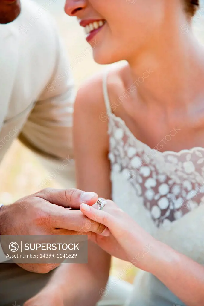 Newlyweds looking at wedding ring, close up